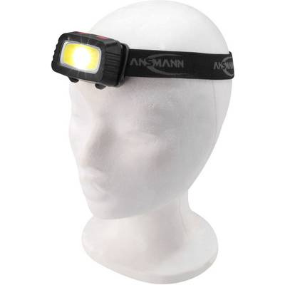 Modèle de tête avec lampe frontale éclairée, fixée à une bande élastique portant le logo 'Ansmann'.