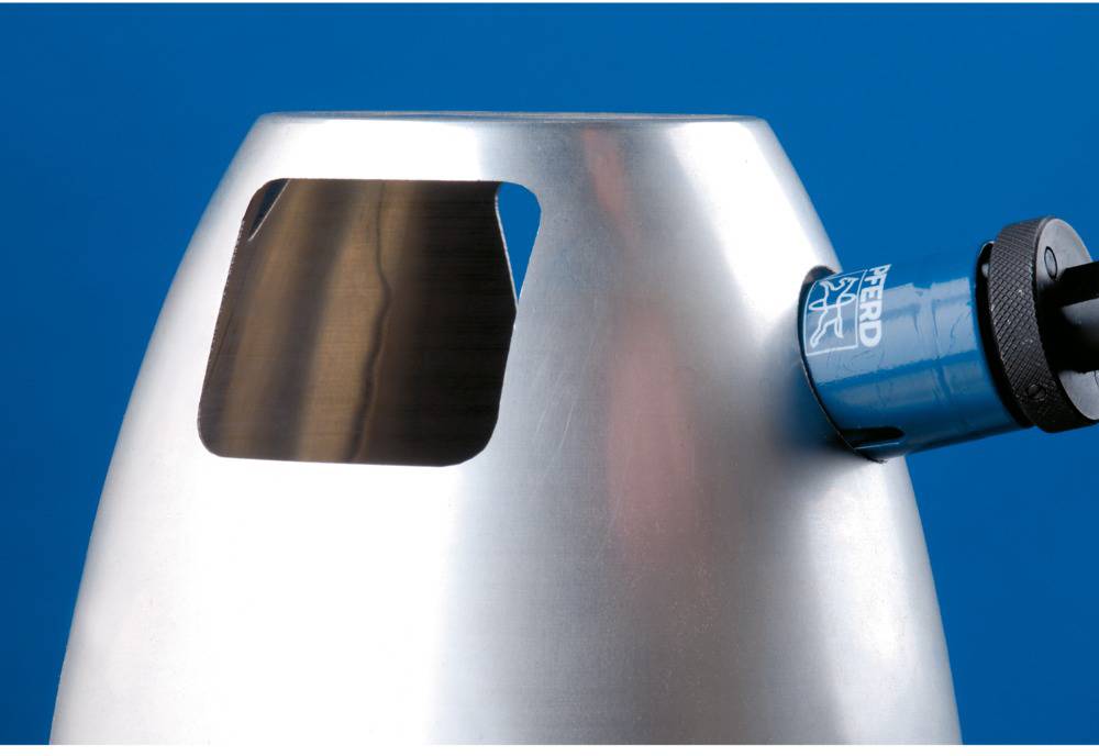 Un cylindre métallique argenté avec une découpe rectangulaire et un dispositif bleu sur le côté droit, sur un fond bleu.