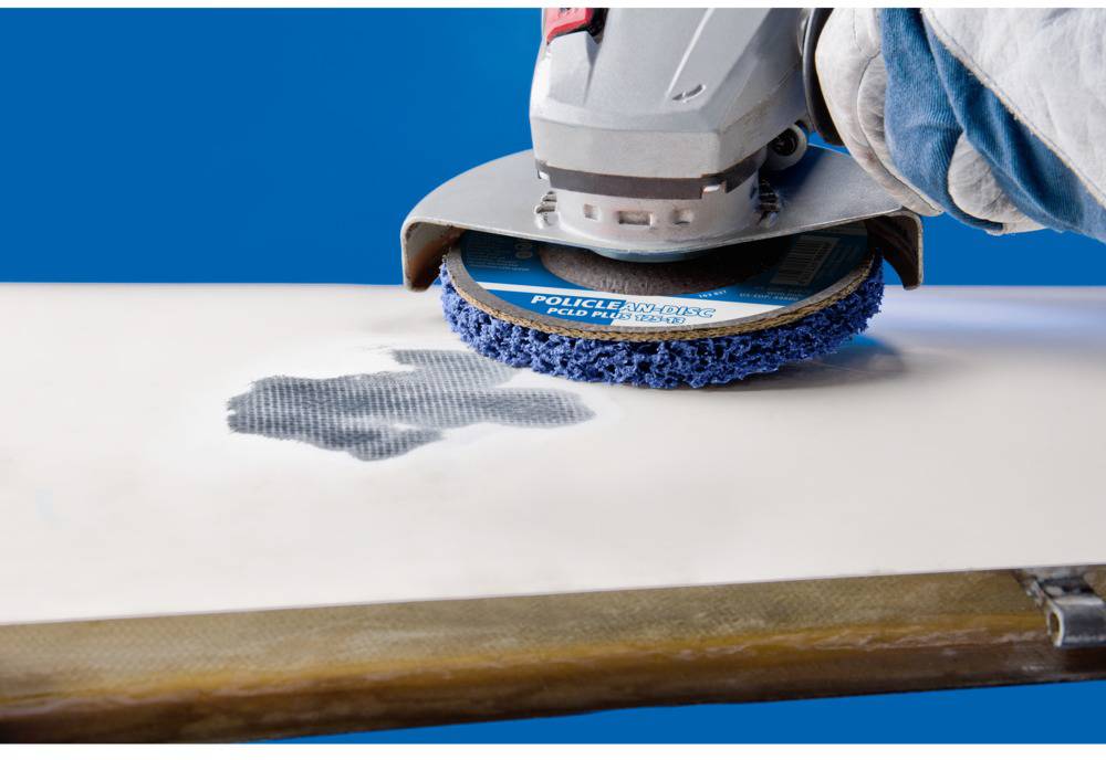 Une personne ponce une surface blanche à l'aide d'une ponceuse électrique, reconnaissable à son tampon de ponçage bleu.