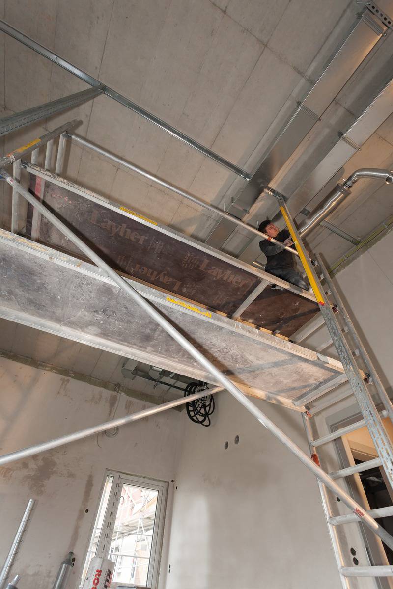 Ouvrier sur un échafaudage travaillant au plafond d'un chantier en construction.