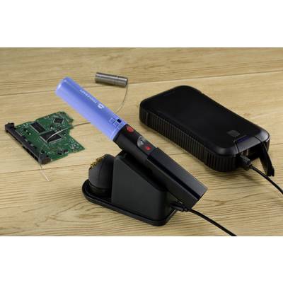 Fer à souder à pointe bleue, branché à un appareil noir, à côté d'une carte électronique verte et d'accessoires de soudure sur une table en bois.