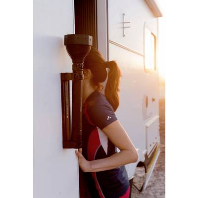 Une personne se penche à la porte d'un camping-car au coucher du soleil. Elle porte des vêtements de sport et regarde au loin.