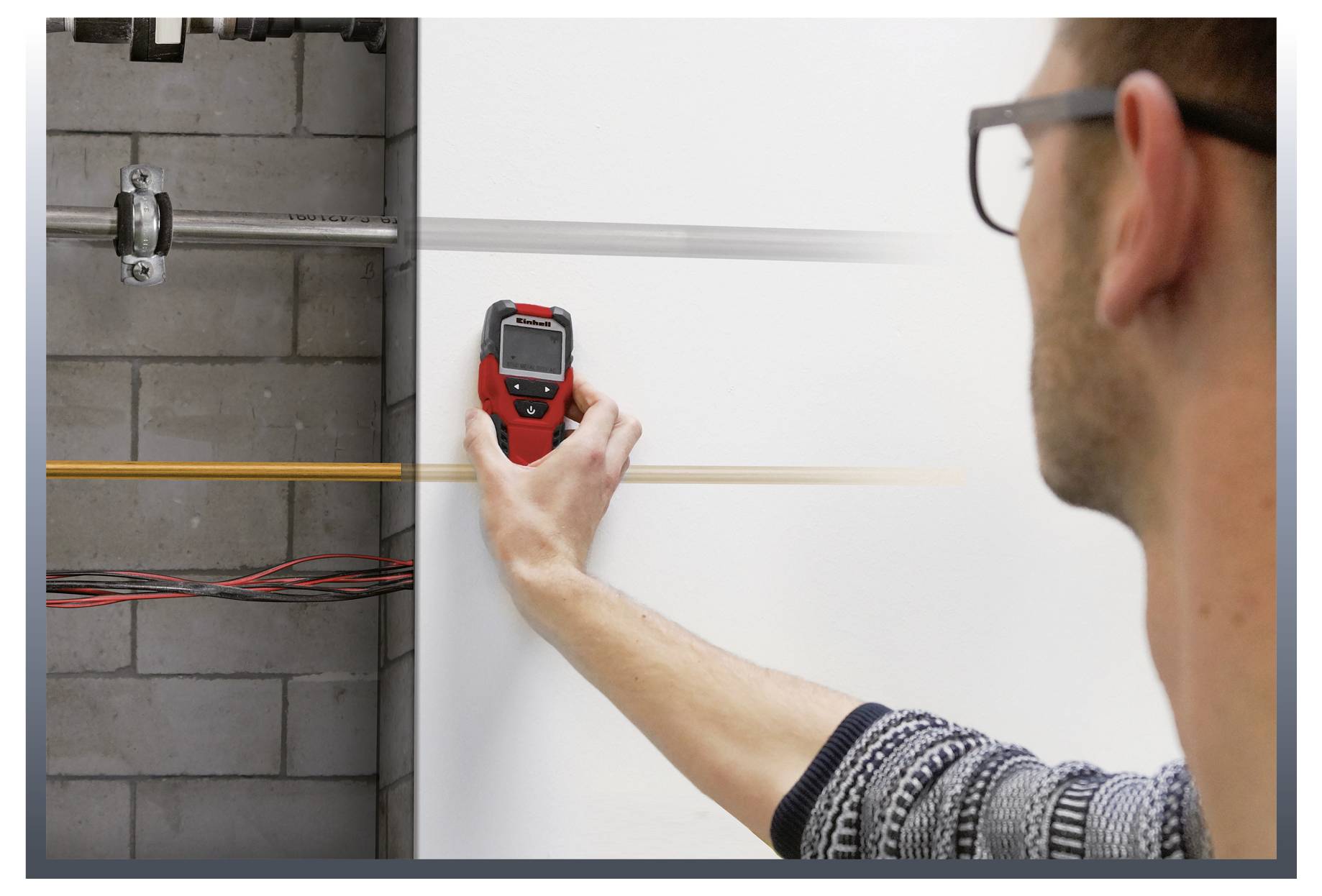 Un homme utilise un détecteur numérique sur un mur pour localiser des conduites. Sur le côté gauche, des câbles et des tuyaux sont visibles.