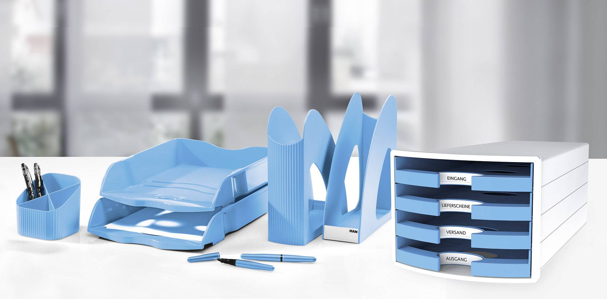Ensemble de rangement de bureau posé sur un bureau, comprenant un pot à crayons, des plateaux de rangement, un organiseur vertical et un classeur à tiroirs en bleu.