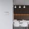 Salle de réunion moderne avec des touches de bois, quatre chaises blanches autour d'une table et trois suspensions au-dessus d'un plan de travail.