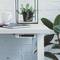 Une table blanche avec une tasse, un carnet et un pot de plantes succulentes. Un appareil réseau est fixé sous le bord de la table.