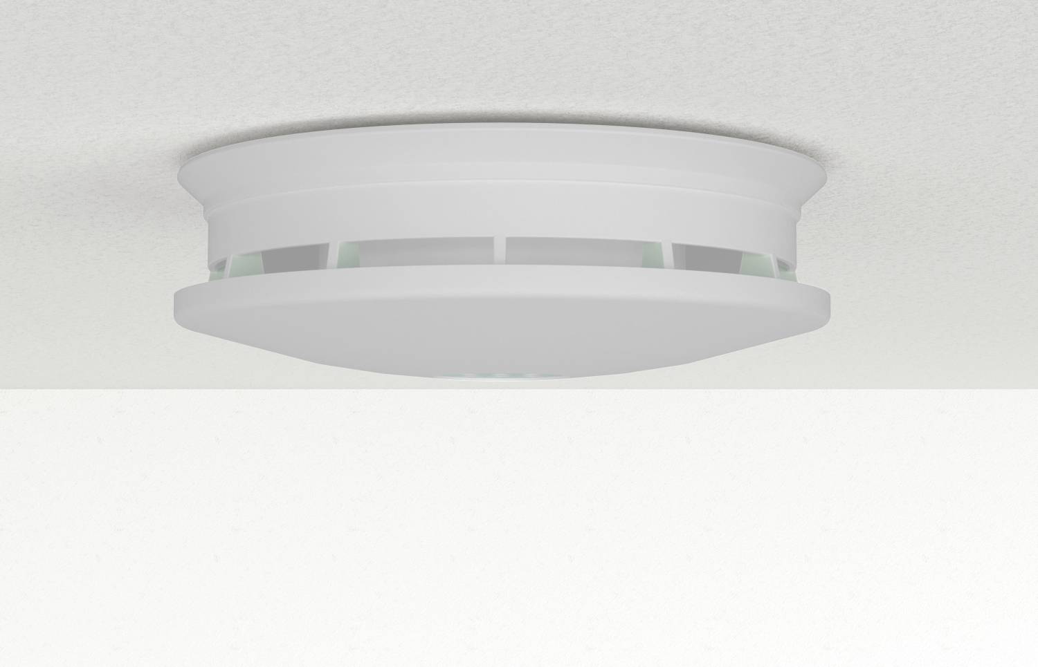 Détecteur de fumée blanc et rond monté au plafond, vu de dessous.
