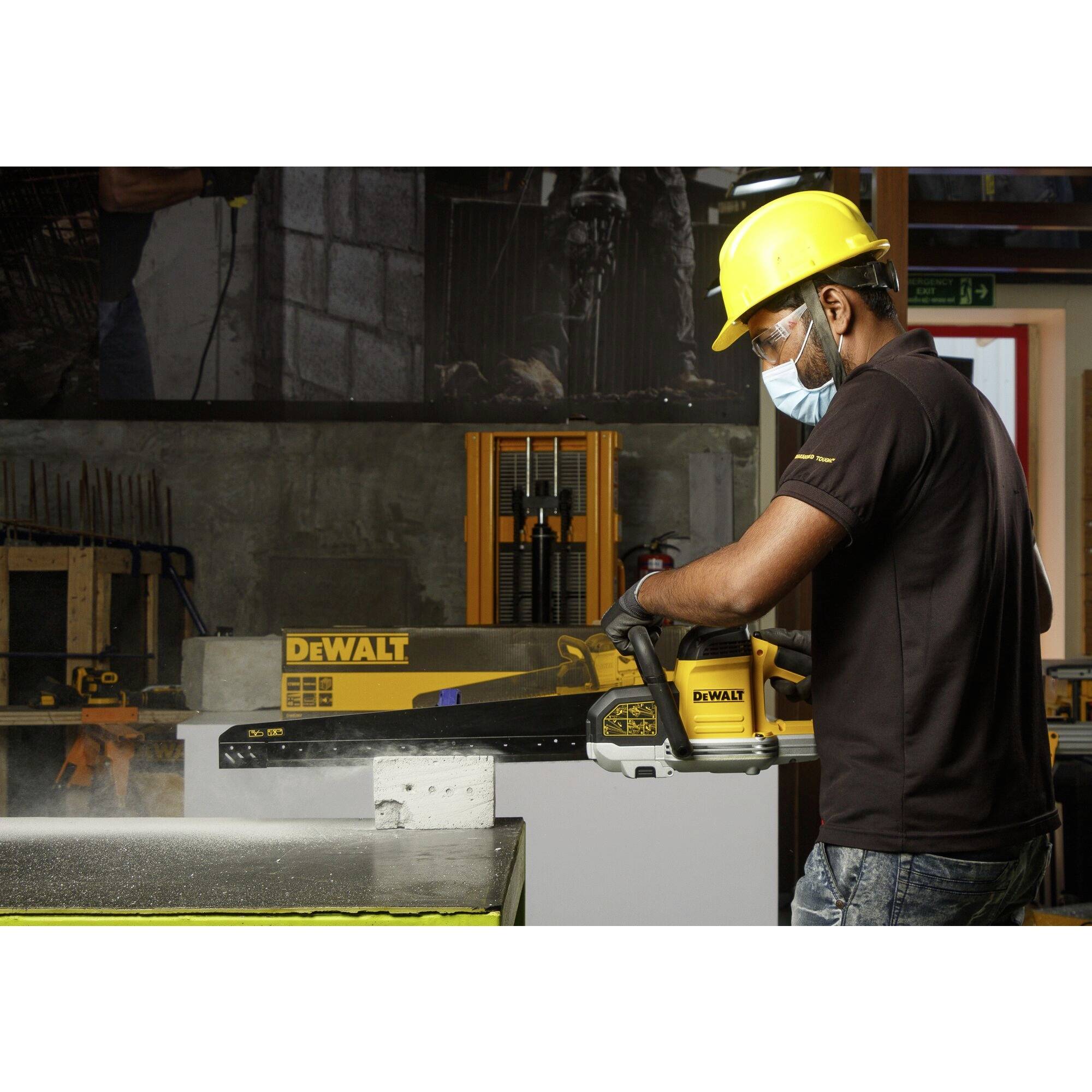 Un ouvrier porte un casque et un masque de protection et utilise un outil DeWalt pour couper un matériau dans un atelier.