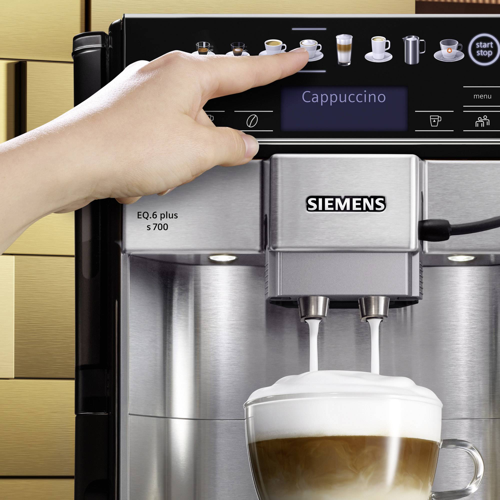 Une main actionne une machine à café Siemens pour préparer un cappuccino. Une tasse de cappuccino est placée sous le bec verseur.