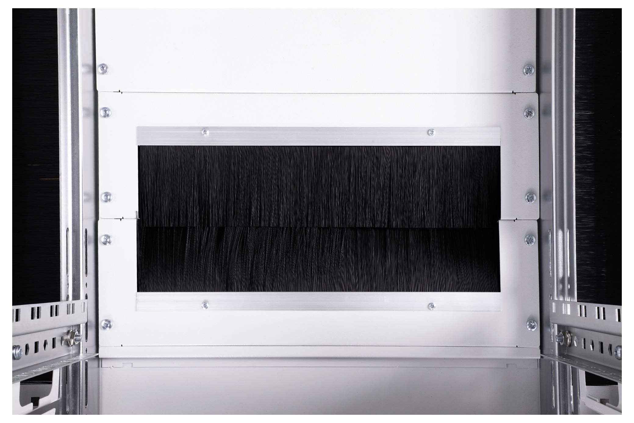 Barrette de brosse noire dans un cadre métallique blanc, probablement un élément d'un passe-câbles dans une armoire serveur ou technique.