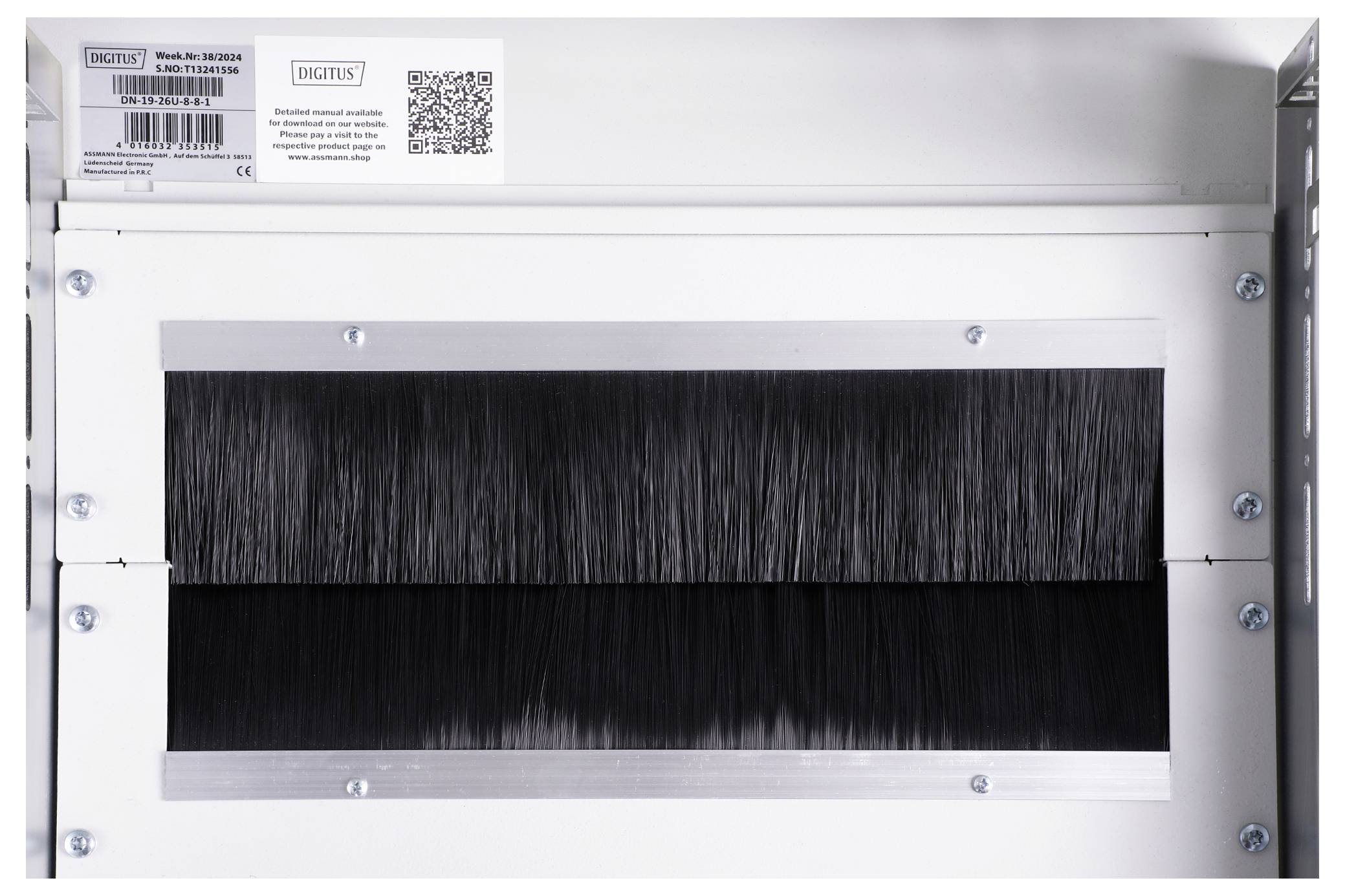 Un appareil blanc avec une bande de poils noirs au milieu. Un code QR et un autocollant avec du texte en haut à gauche.