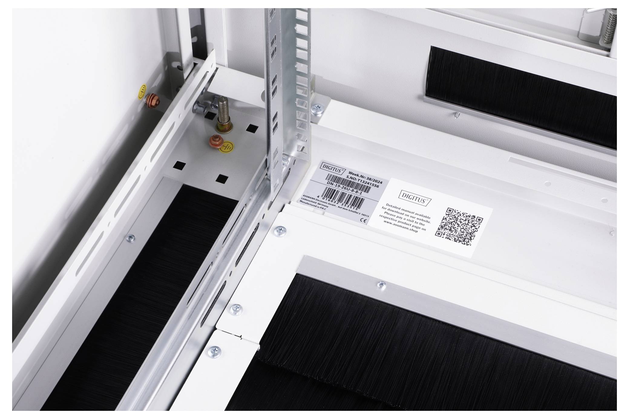 Un système d'armoire électrique avec un joint à brosse noir, un code QR et un numéro de série sur une plaque à l'intérieur.