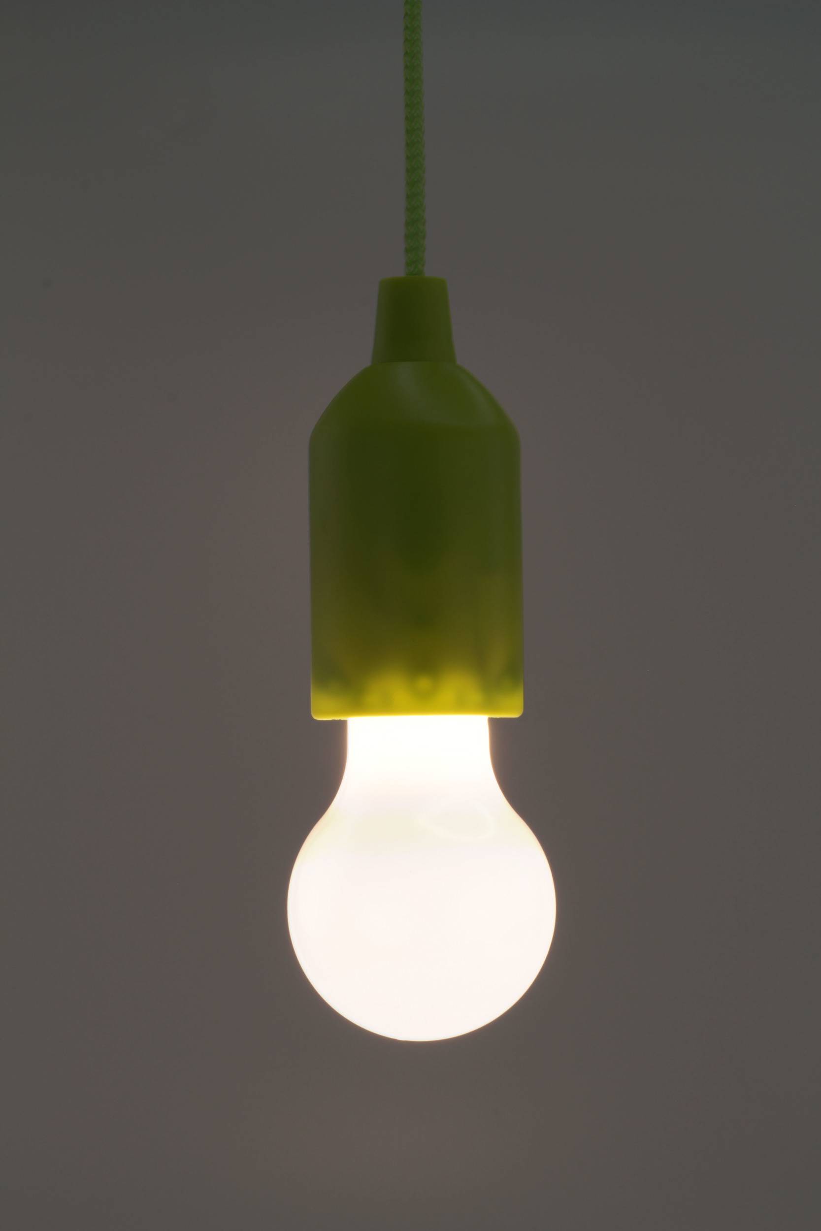 Une unique ampoule lumineuse pend du plafond, suspendue dans un espace au design minimaliste.