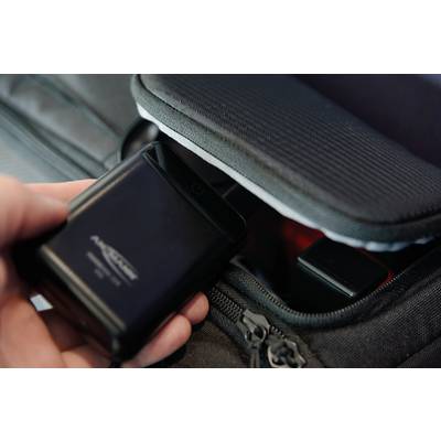 Une personne place un chargeur portable dans une pochette matelassée noire d'un sac.