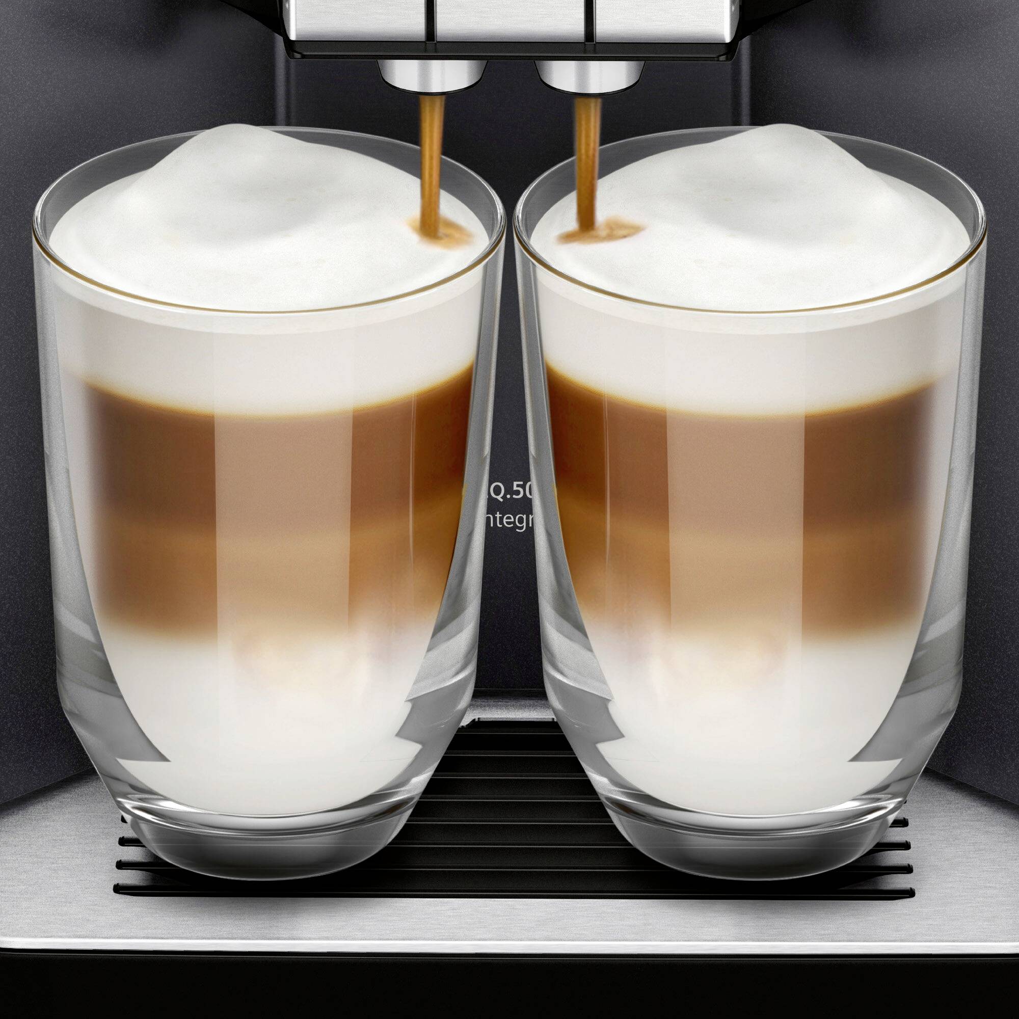 Une machine à espresso remplit deux verres de cappuccino. Les couches d'espresso et de mousse sont clairement visibles.