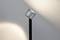 Une lampe sur pied moderne avec une tête pivotante qui projette une lumière indirecte sur un mur.