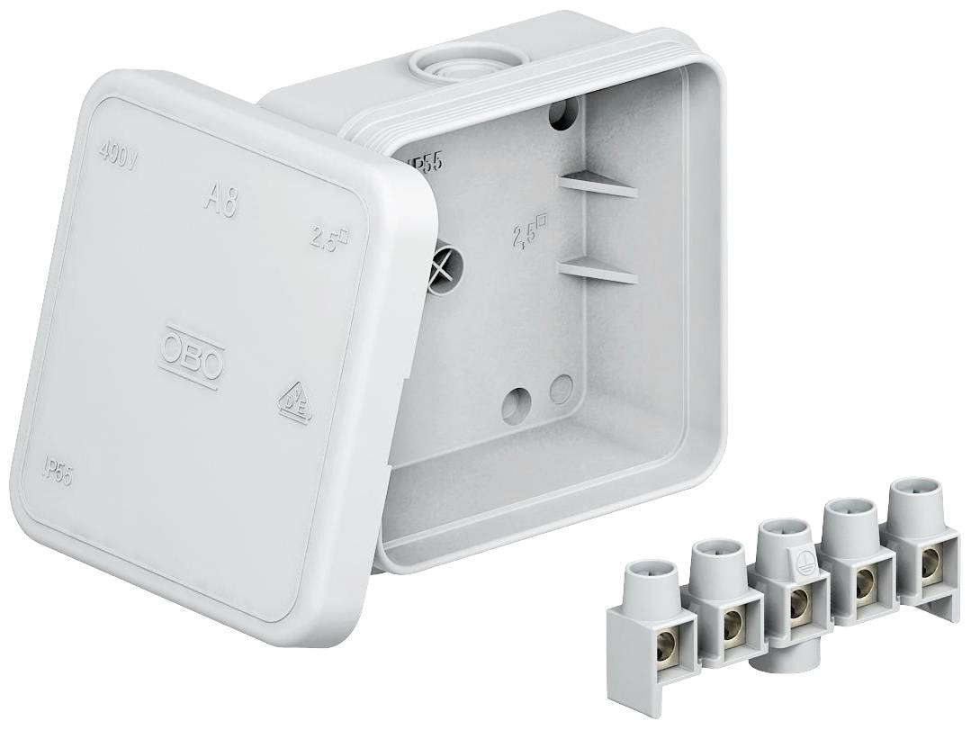 Une boîte de distribution électrique grise, carrée, avec un couvercle amovible, à côté d'un bloc de connexion blanc pour les raccordements de câbles.