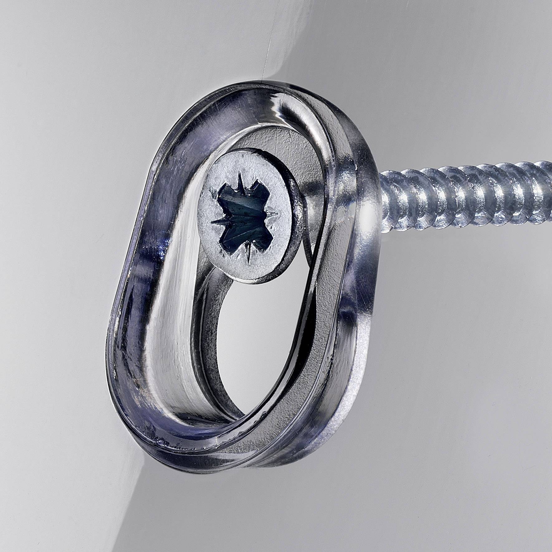 Une vis en argent avec un œillet ovale est vissée dans un mur gris. L'œillet est légèrement incliné.