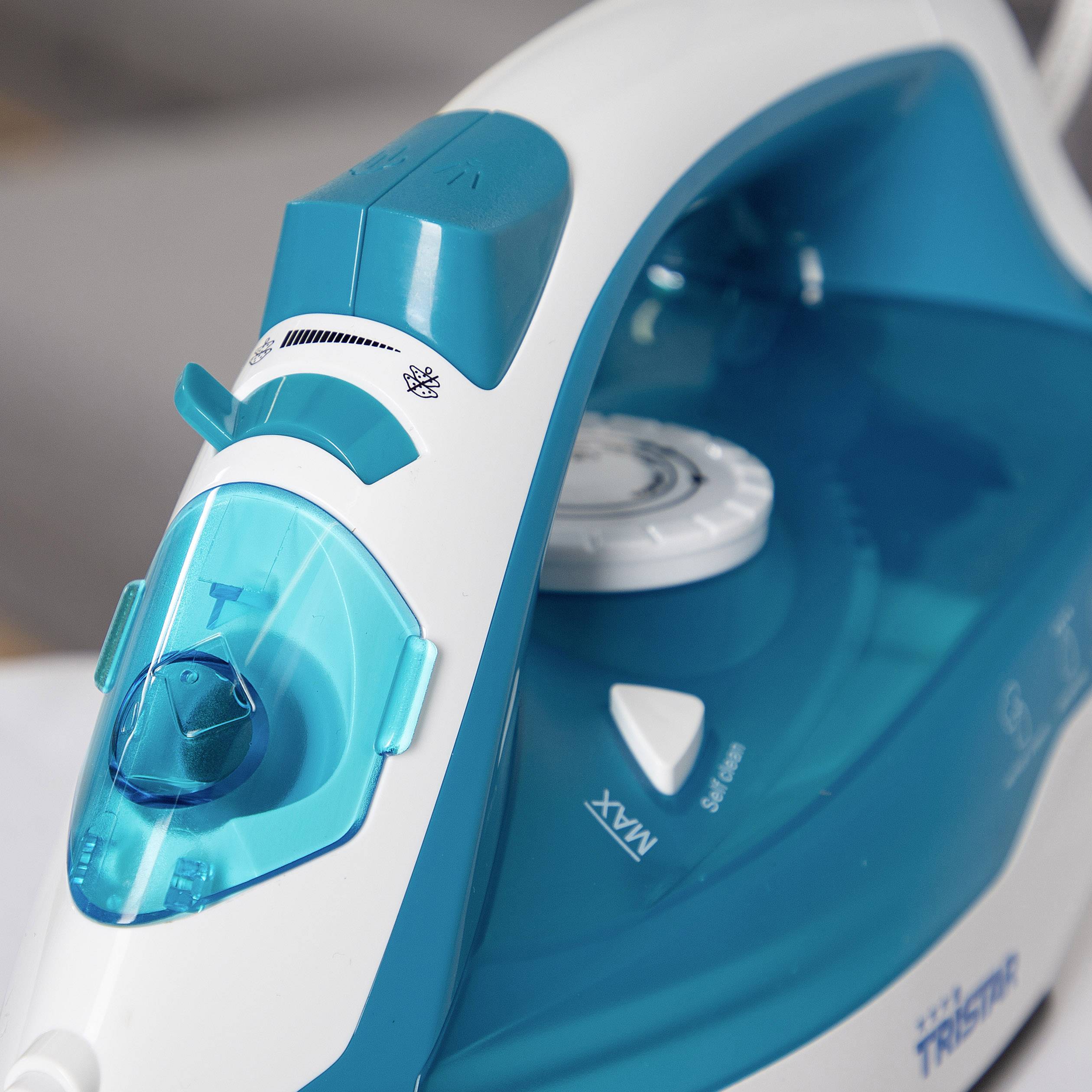 Fer à repasser électrique à vapeur en gros plan, design bleu et blanc, niveau maximal réglé sur le bouton rotatif.