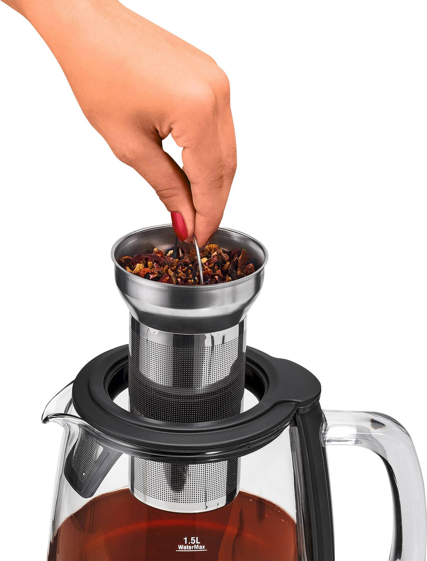 Une main tient un passoire à thé au-dessus d'une carafe en verre remplie de thé infusé.