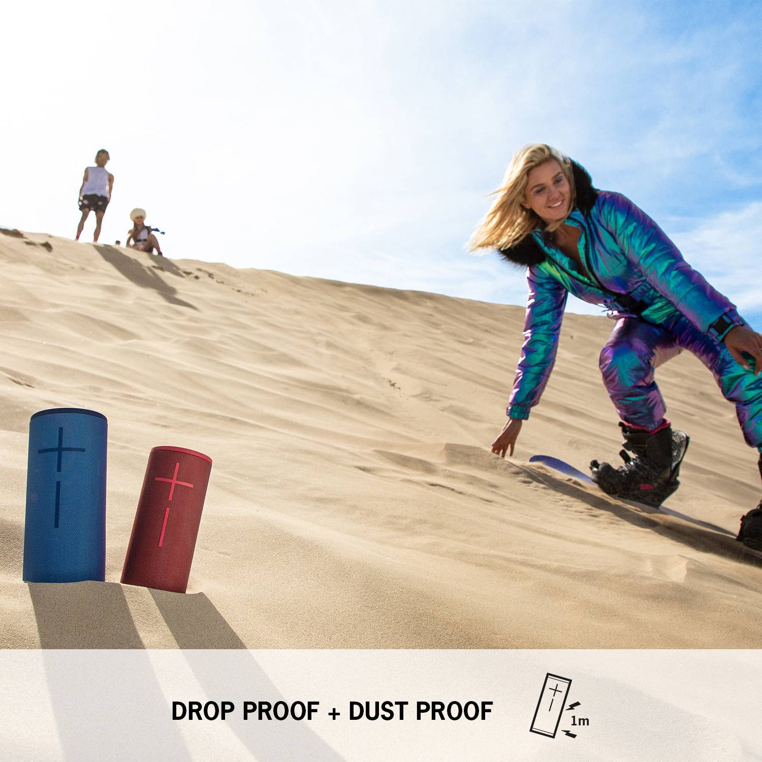 Femme en costume scintillant faisant du snowboard sur une dune de sable. Au premier plan, deux haut-parleurs, texte 'ANTICHUTE + PROTÉGÉ CONTRE LA POUSSIÈRE'.