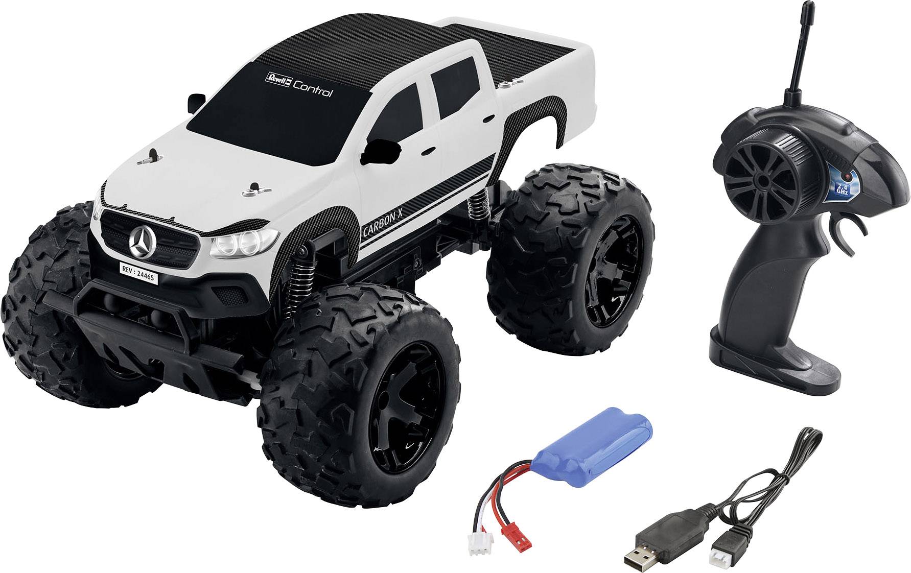 Voiture télécommandée blanche avec toit noir et grandes roues, télécommande, batterie bleue et câble de chargement USB à côté.