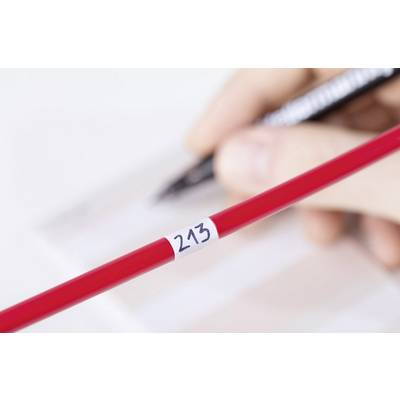 Une main écrit avec un stylo noir sur du papier. Au premier plan, un crayon rouge portant le numéro '243' est posé.