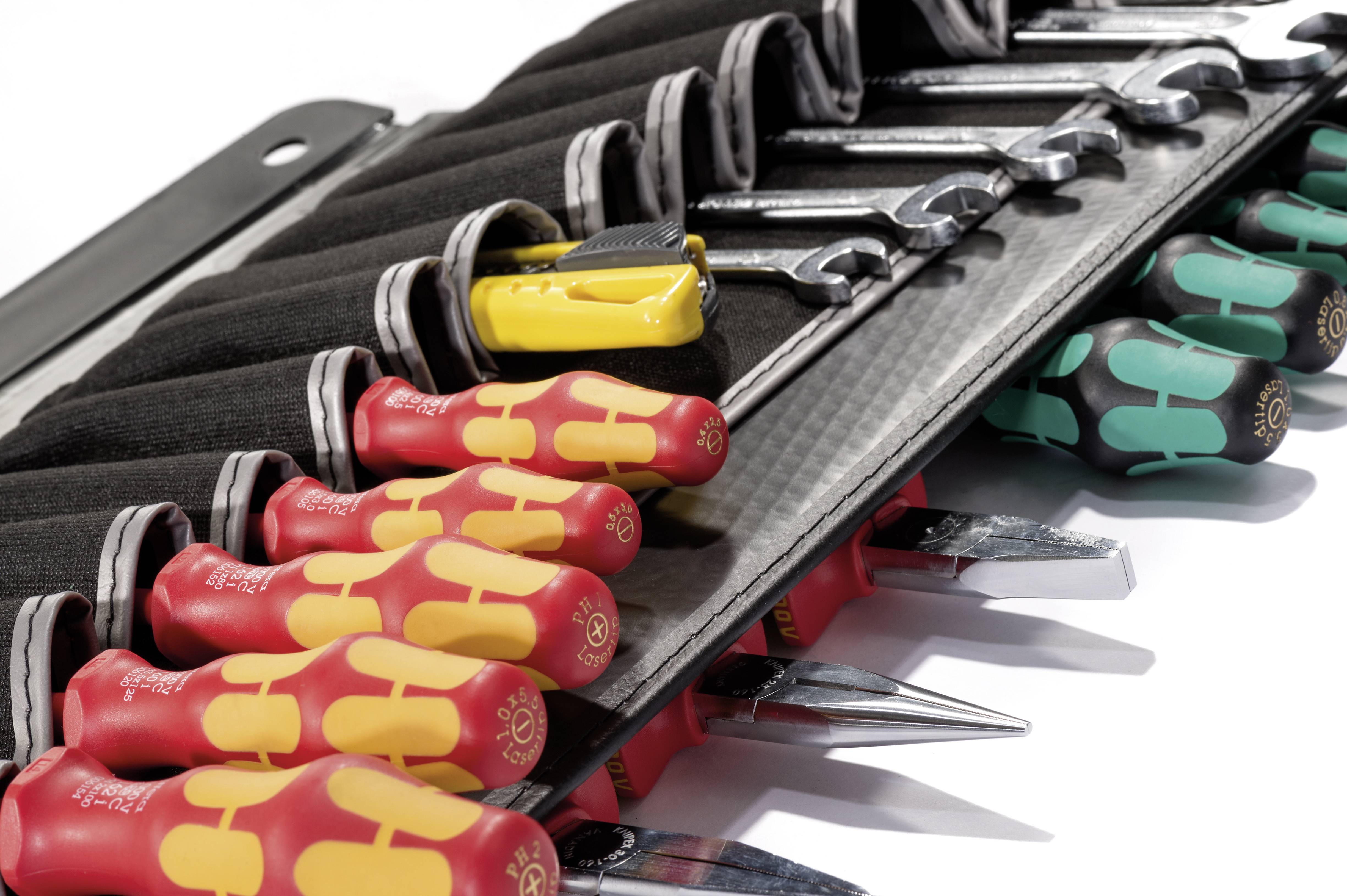 Trousse à outils contenant des tournevis, des clés et un mètre ruban jaune. Les outils sont soigneusement rangés.