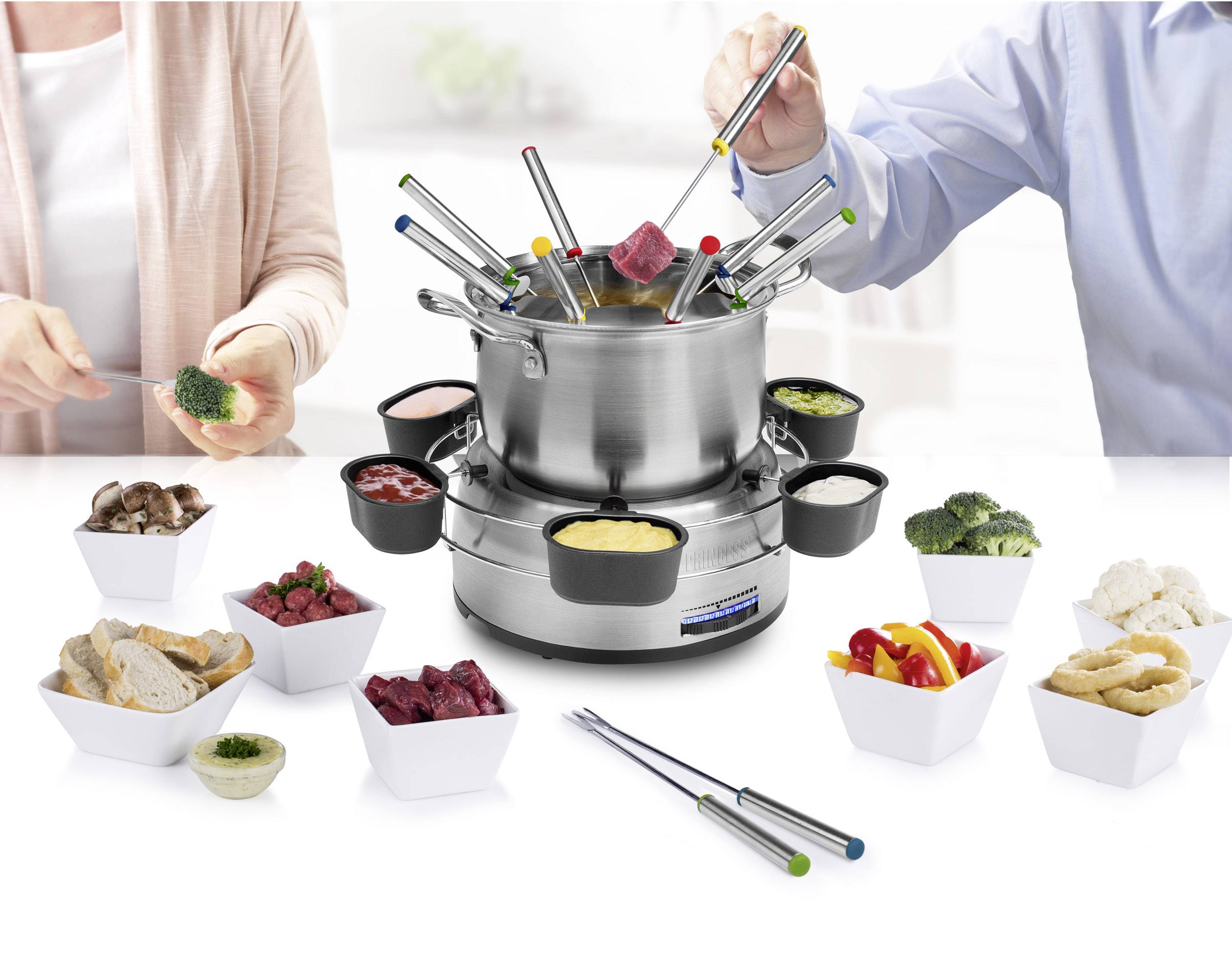 Des personnes préparent ensemble un fondue avec des légumes, de la viande et des morceaux de pain. Différents bols de sauce entourent la casserole.