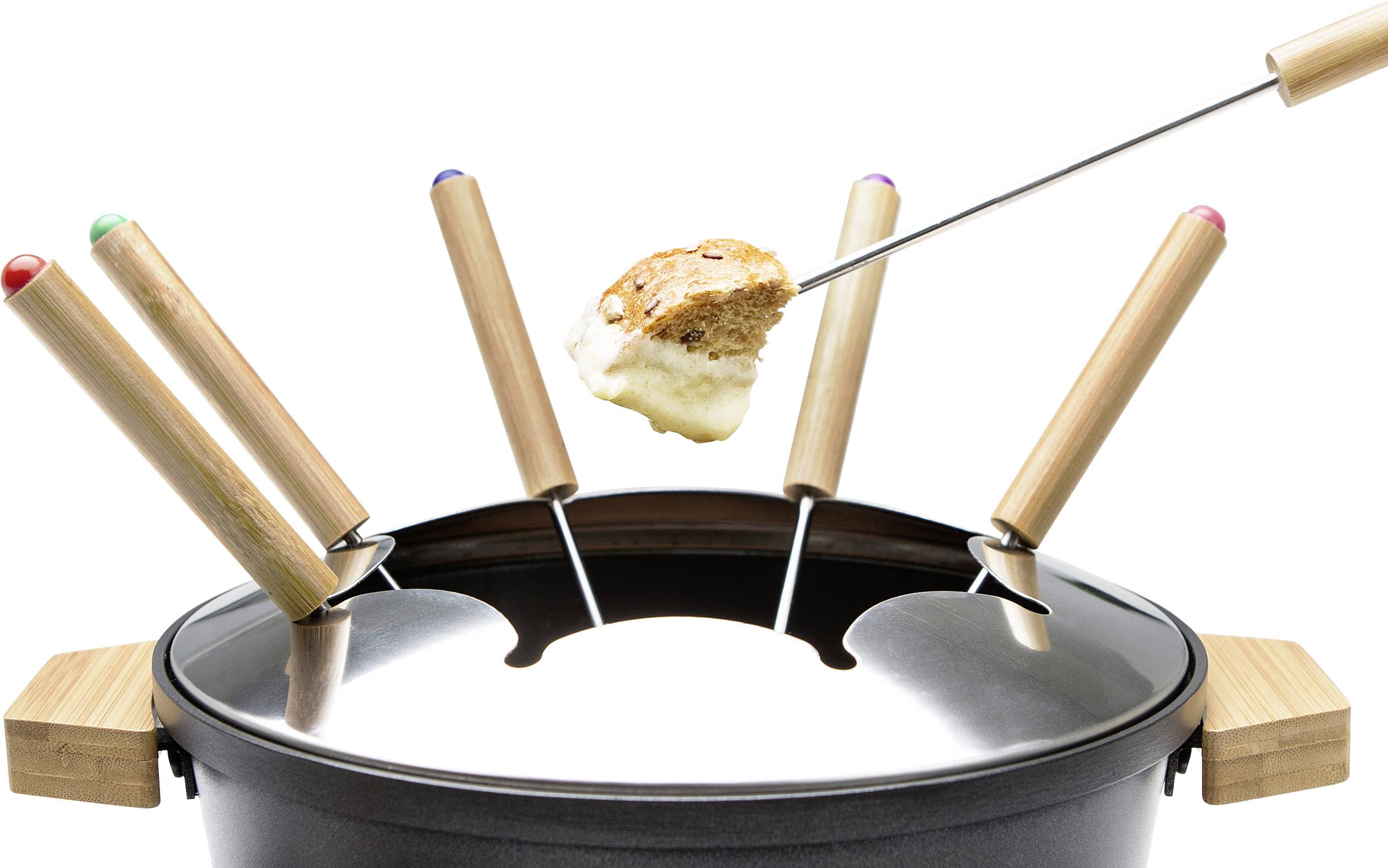 Plusieurs fourchettes à fondue sont plantées dans un caquelon. Une fourchette tient un morceau de pain recouvert de fromage fondu.