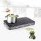 Une main remue un potage avec une cuillère en bois dans une casserole posée sur une plaque de cuisson à induction moderne. À côté, se trouvent des poivrons et du brocoli.