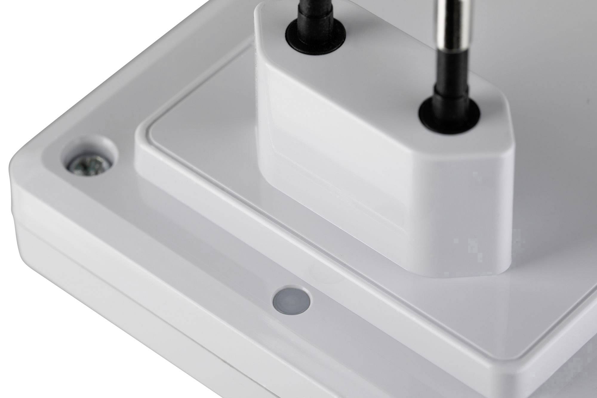 Gros plan d'une fiche électrique blanche dans une prise de courant. La mise au point est faite sur les parties en plastique et les broches métalliques de la fiche.