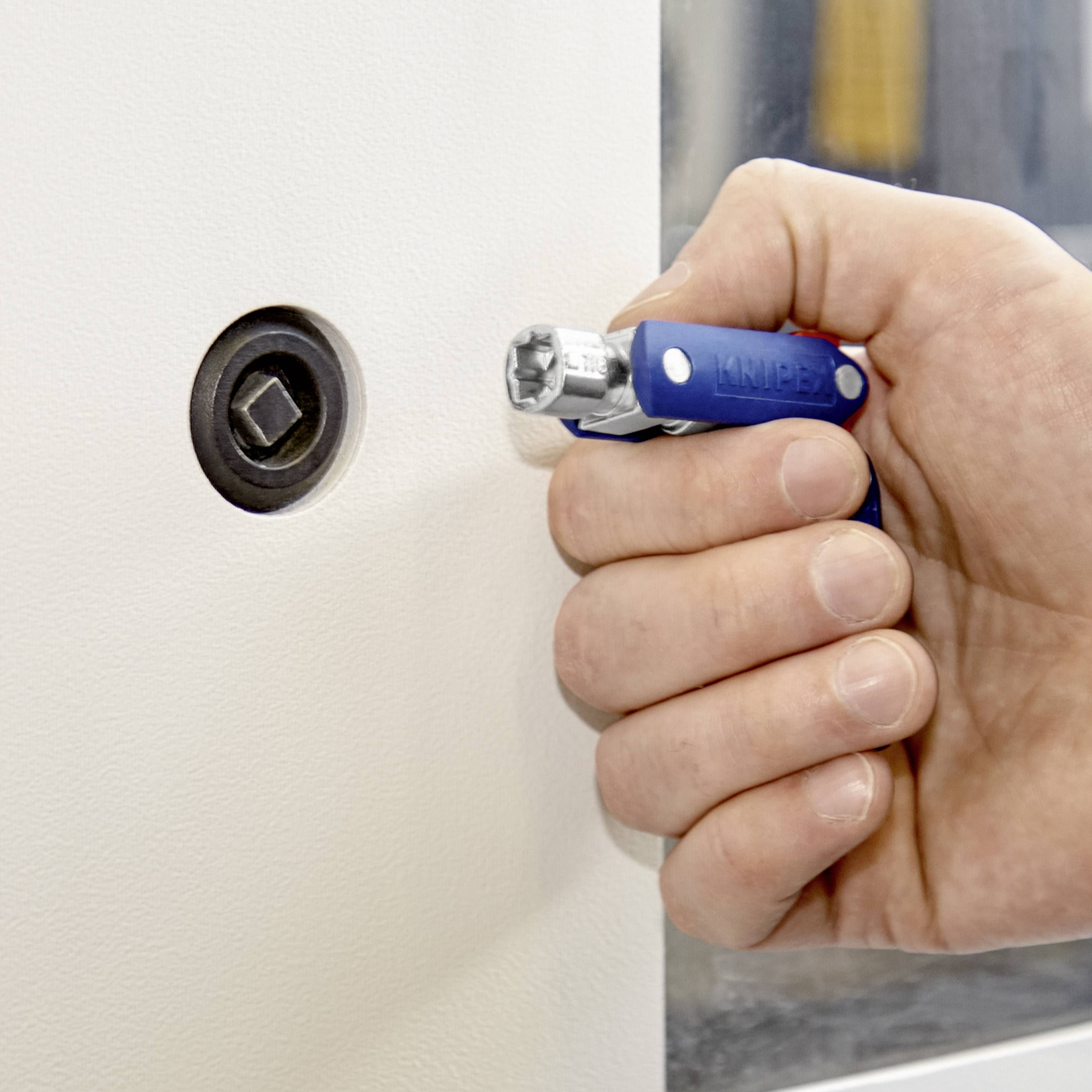 Une main tient un outil multifonction bleu qui est inséré dans une serrure avec une ouverture en forme d'étoile.