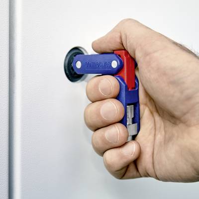 Une main tourne une poignée bleue et rouge afin de déplacer un verrou cylindrique vers une position de fermeture. Le mur et l'arrière-plan sont flous.