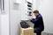 Un technicien travaille sur un armoire électrique ouverte, tandis qu'une boîte à outils est posée sur un carton.