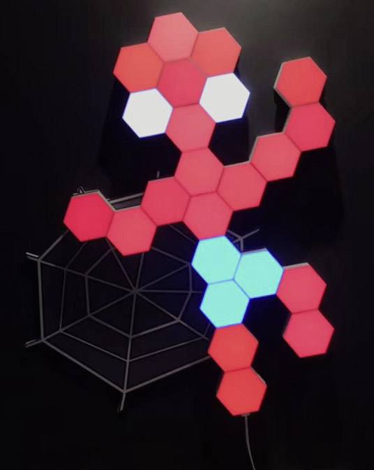 Une œuvre d'art murale composée de panneaux LED hexagonaux représente une figure rouge sur un réseau métallique en forme de toile d'araignée.