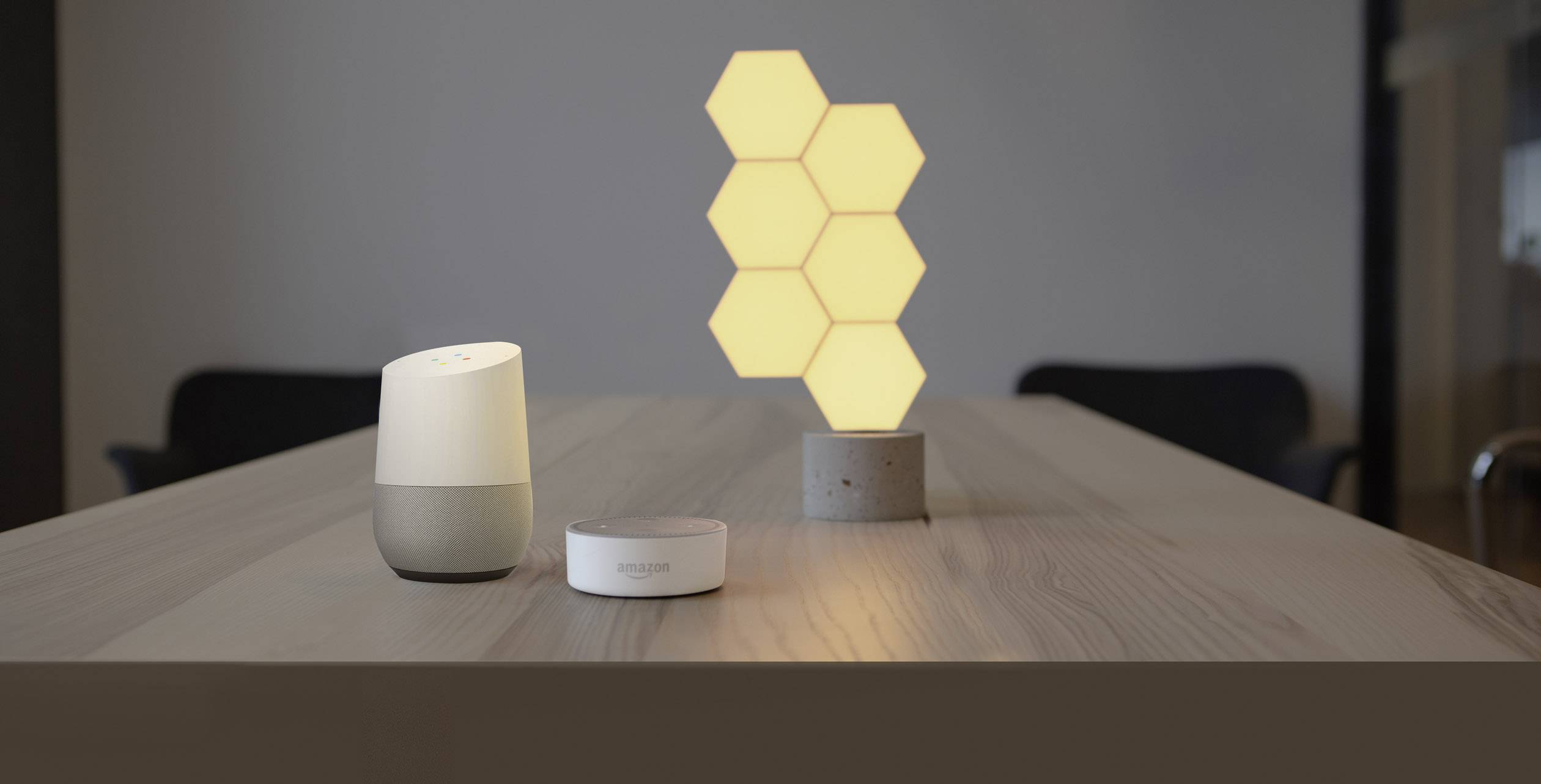Une table avec un haut-parleur intelligent, un assistant vocal et des lumières hexagonales brillantes en arrière-plan.