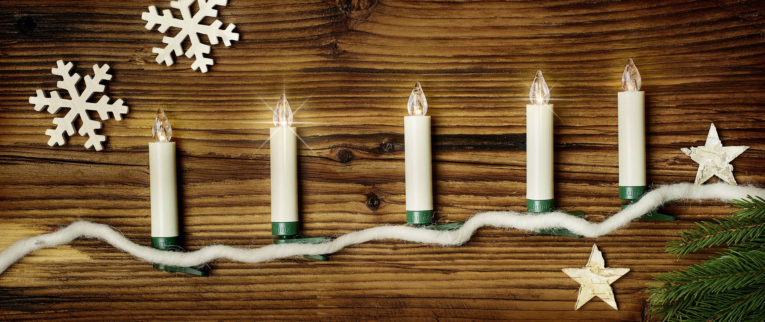 Six bougies électriques sur du bois, décorées de flocons de neige blancs, d'étoiles et de branches de sapin. Décoration de Noël.