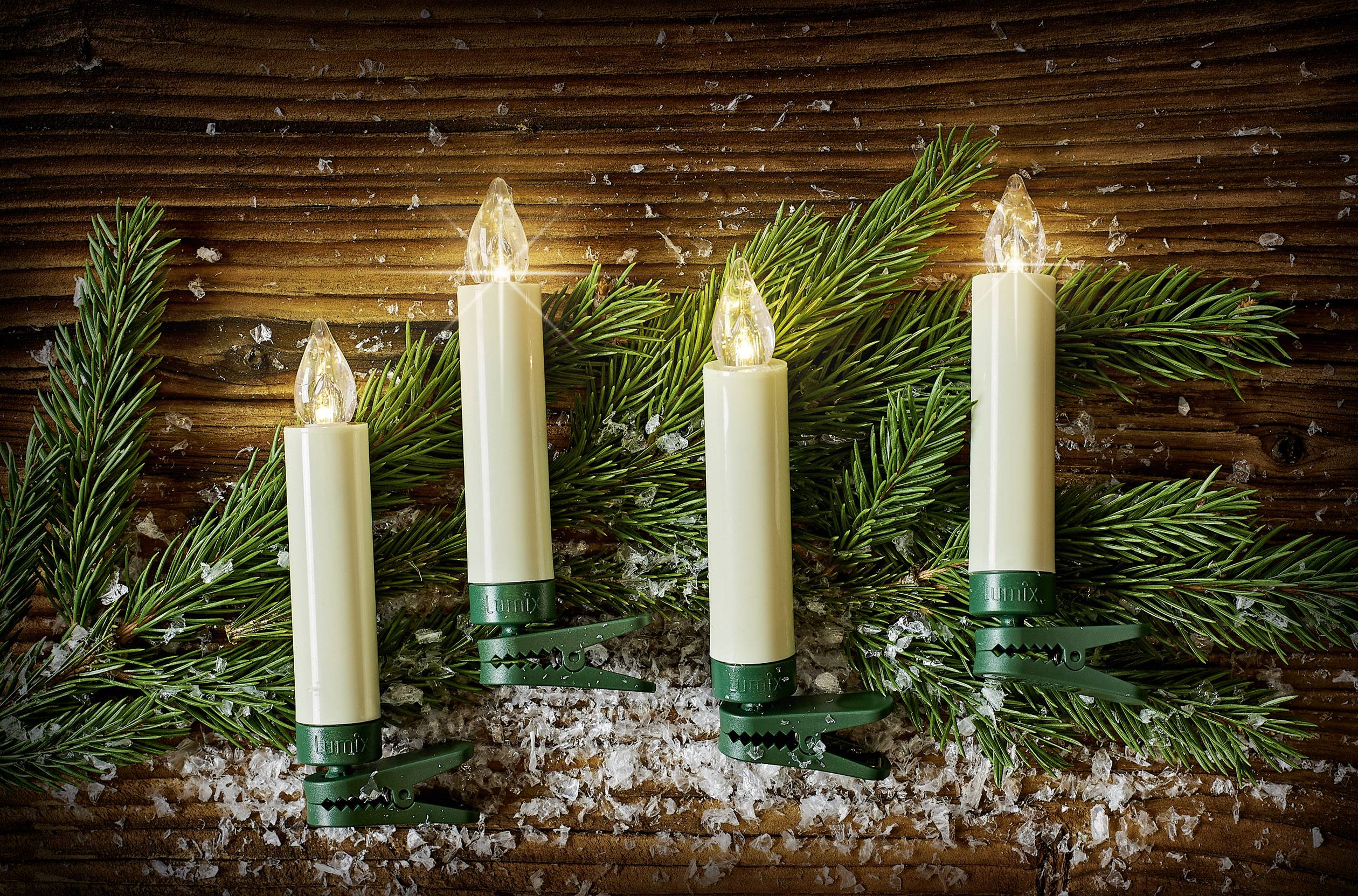 Quatre bougies illuminées avec des pinces vertes sur des branches de sapin, de la neige sur une surface en bois. Décoration festive.