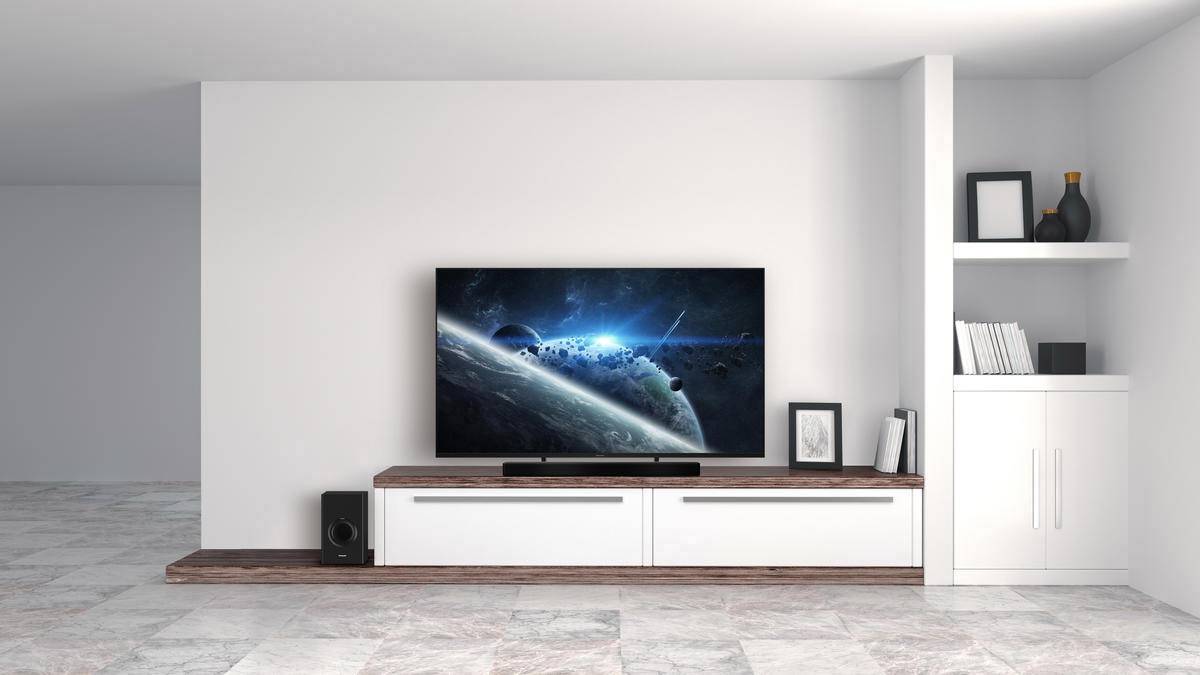 Salon équipé d'un téléviseur à écran plat diffusant une image de l'espace. La pièce est aménagée dans un style moderne avec des éléments blancs et en bois.