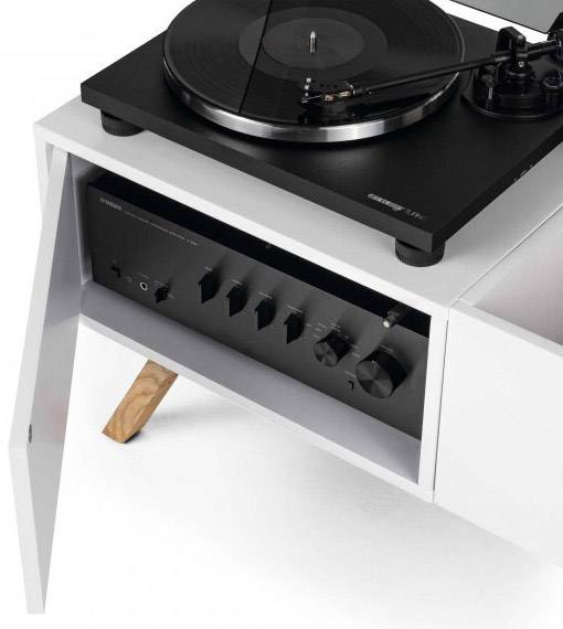 Un tourne-disque posé sur un meuble blanc moderne avec un amplificateur intégré. Le design est élégant et minimaliste.