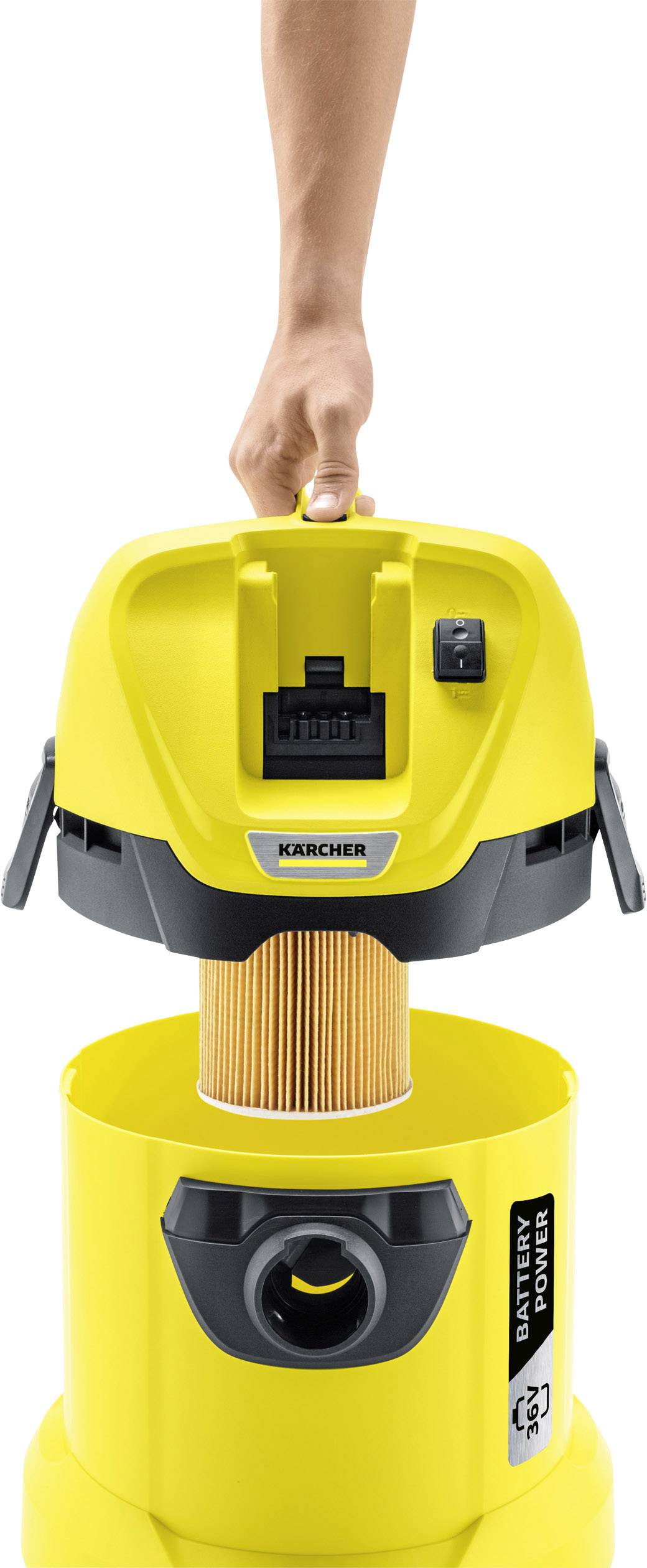 Aspirateur portable jaune avec un couvercle amovible montrant un filtre, tenu par une main par sa poignée.