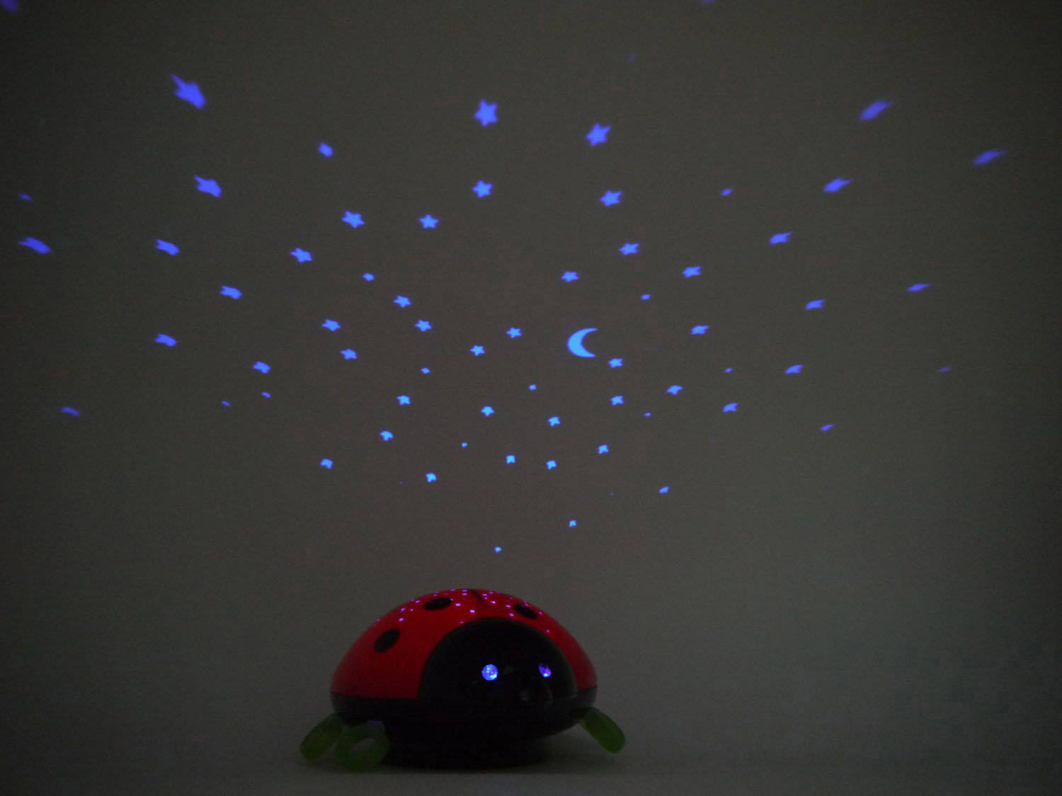 Une veilleuse en forme de coccinelle projette des étoiles bleues et une lune au plafond.