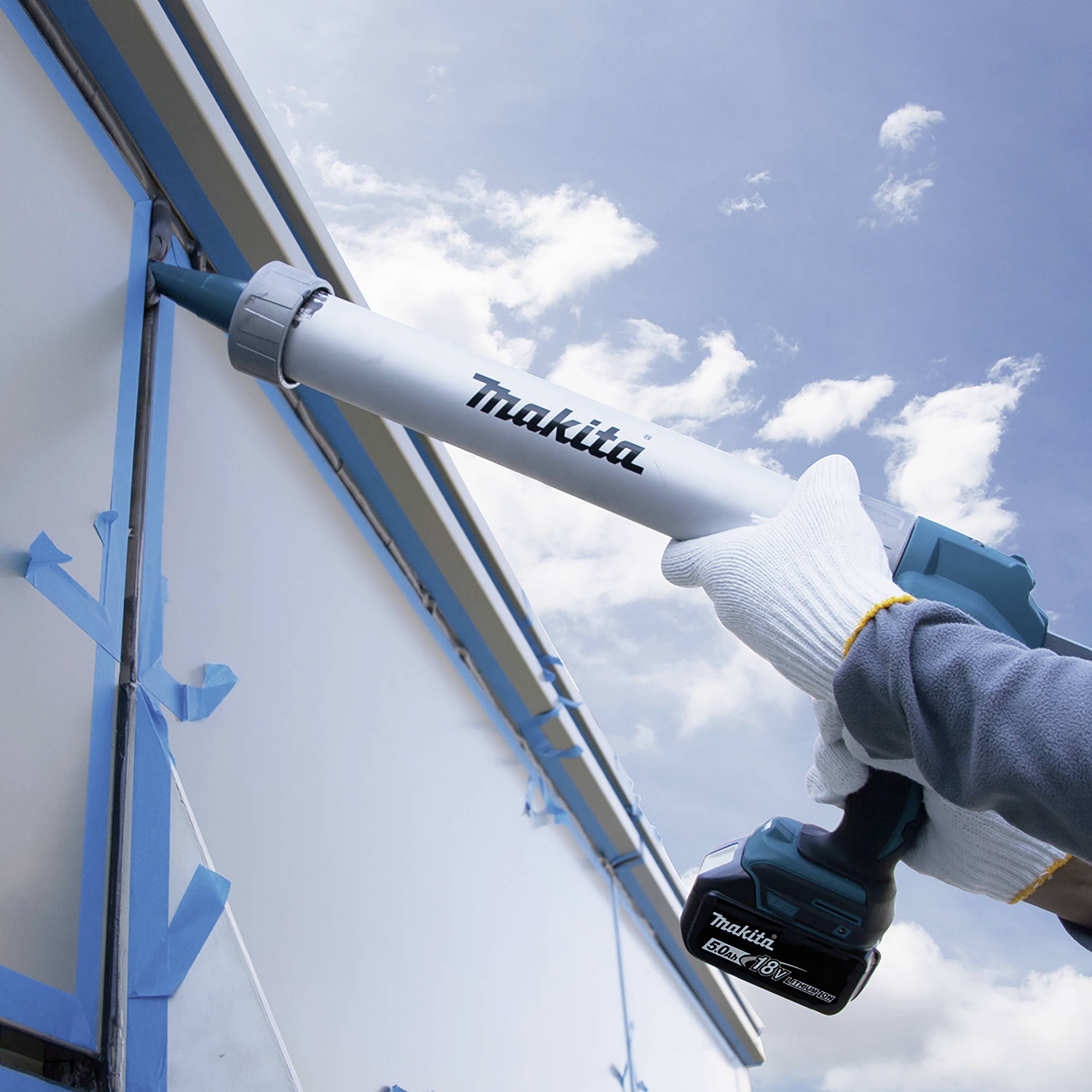 Une personne utilise un pistolet à cartouche électrique pour appliquer précisément un mastic sur un joint de bâtiment.