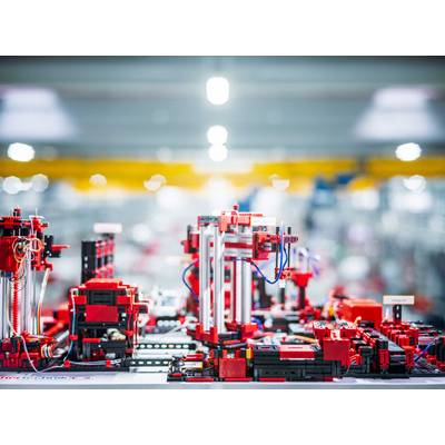 Des robots industriels assemblent des pièces de précision avec de l'équipement rouge et noir sur un fond flou.