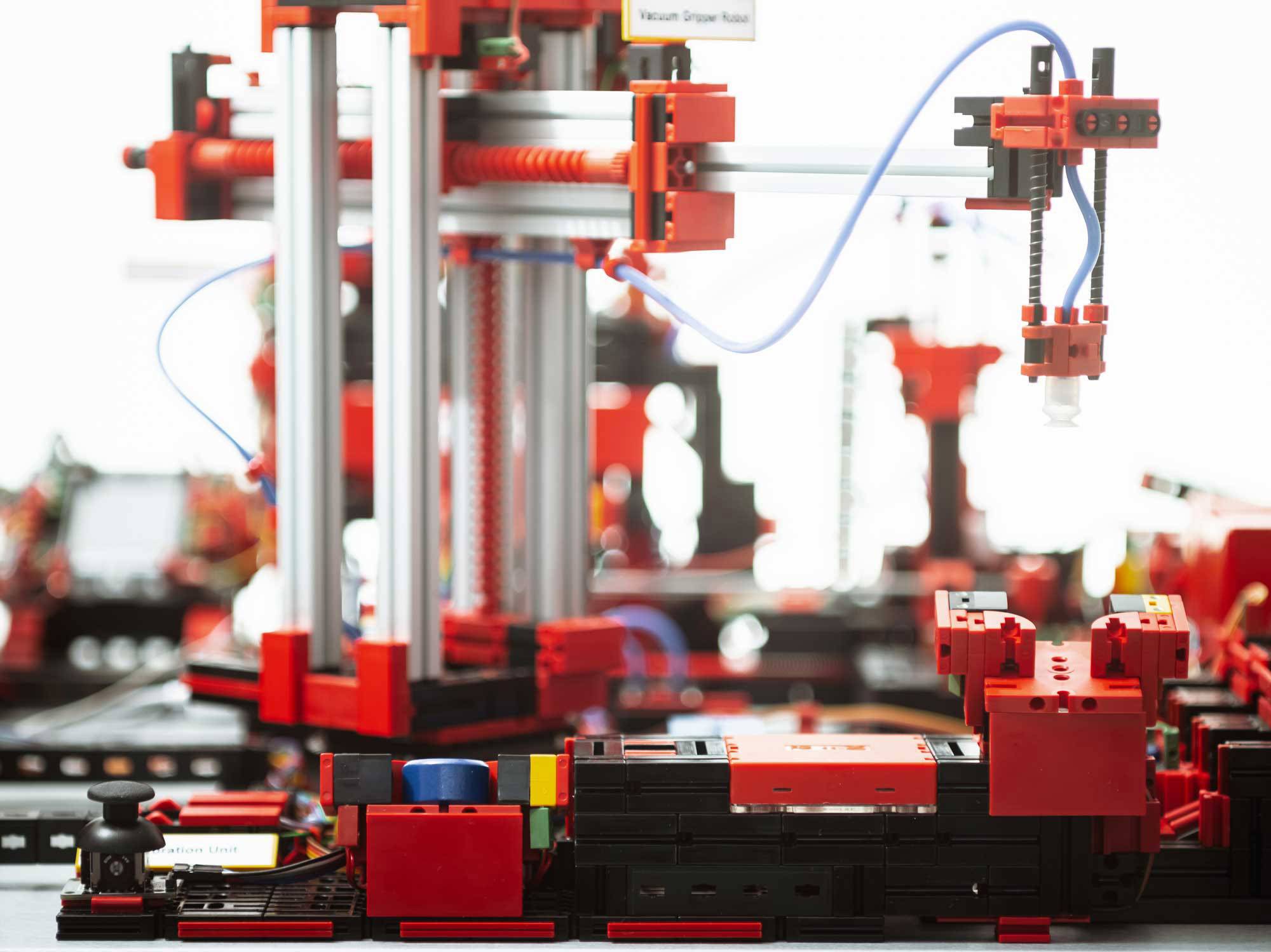 Robot construit à partir de blocs colorés, exécutant des tâches avec précision. Bras mécaniques et fils apparents, construction complexe.