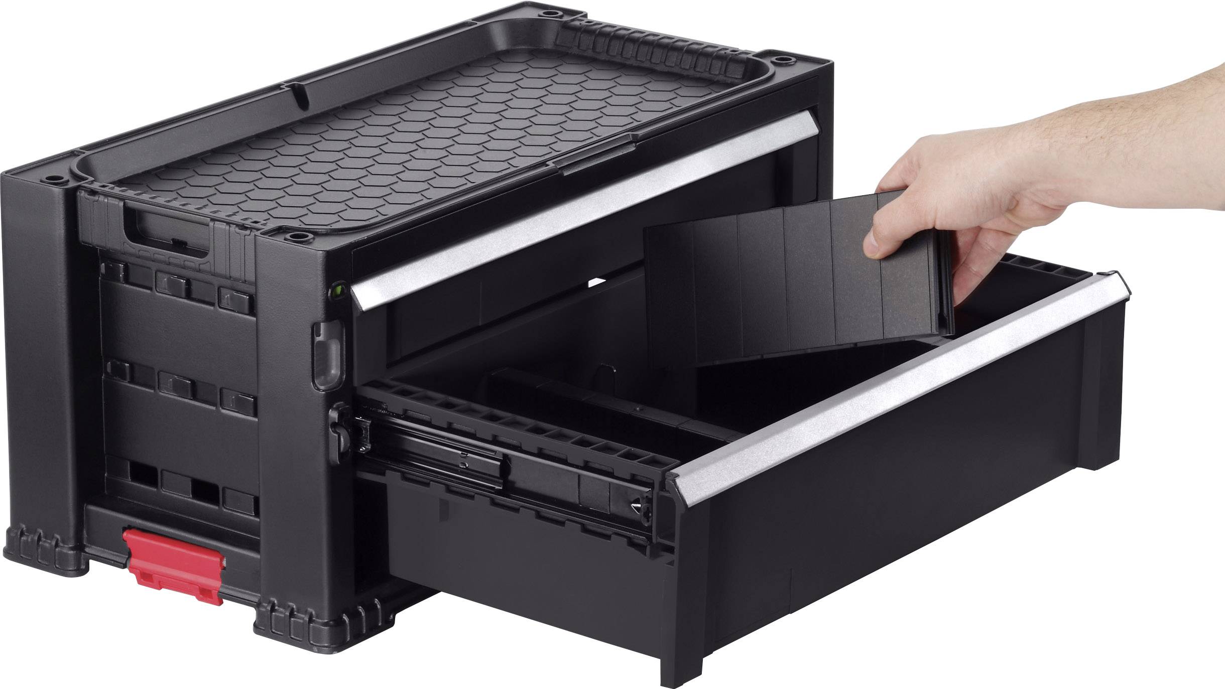 Un coffret d'atelier noir ouvert avec une cloison amovible. Une main tient la cloison au-dessus d'un tiroir.