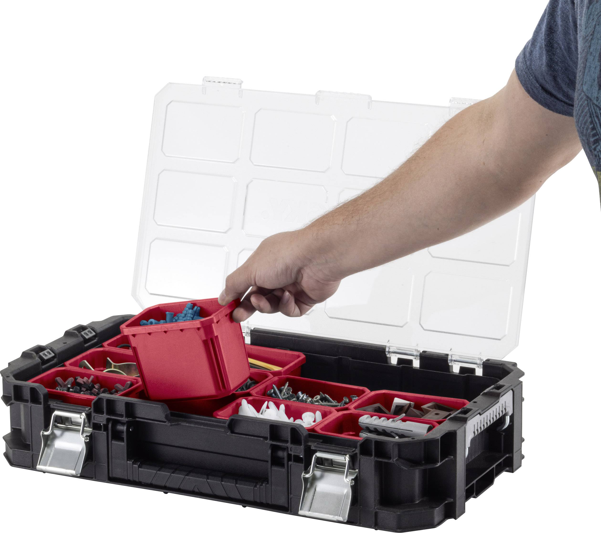 Une main saisit un conteneur rouge dans une boîte à outils ouverte contenant différentes vis et éléments de fixation.