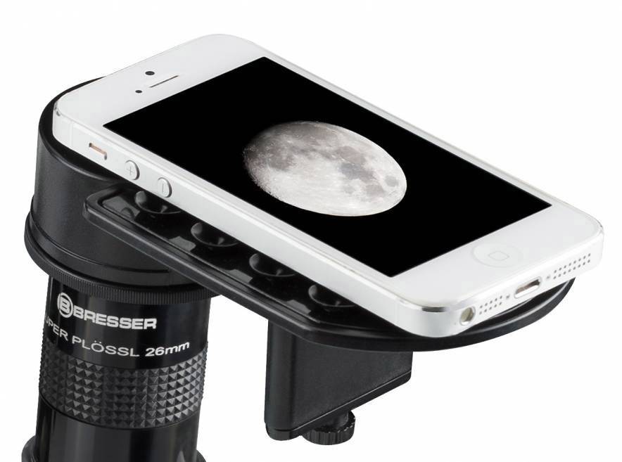 Un smartphone est fixé sur un télescope et affiche une image de la pleine lune sur son écran.