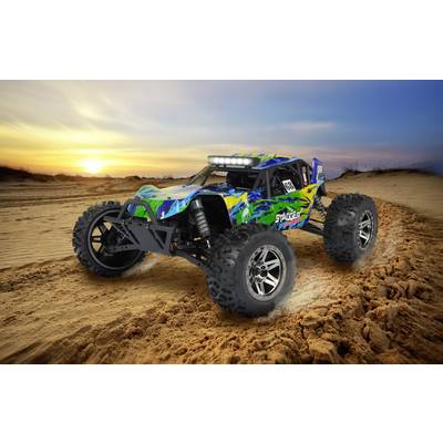Une voiture télécommandée tout-terrain roule rapidement sur un parcours sablonneux hors route au coucher du soleil, ses roues soulevant des nuages de sable.